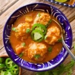Albondigas de Pollo (or Chicken Meatball Soup) served in a decorative Mexican blue plate and topped with cilantro and sliced jalapeno.