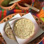 Two Mexican Gorditas plated on a decorative red clay plate.
