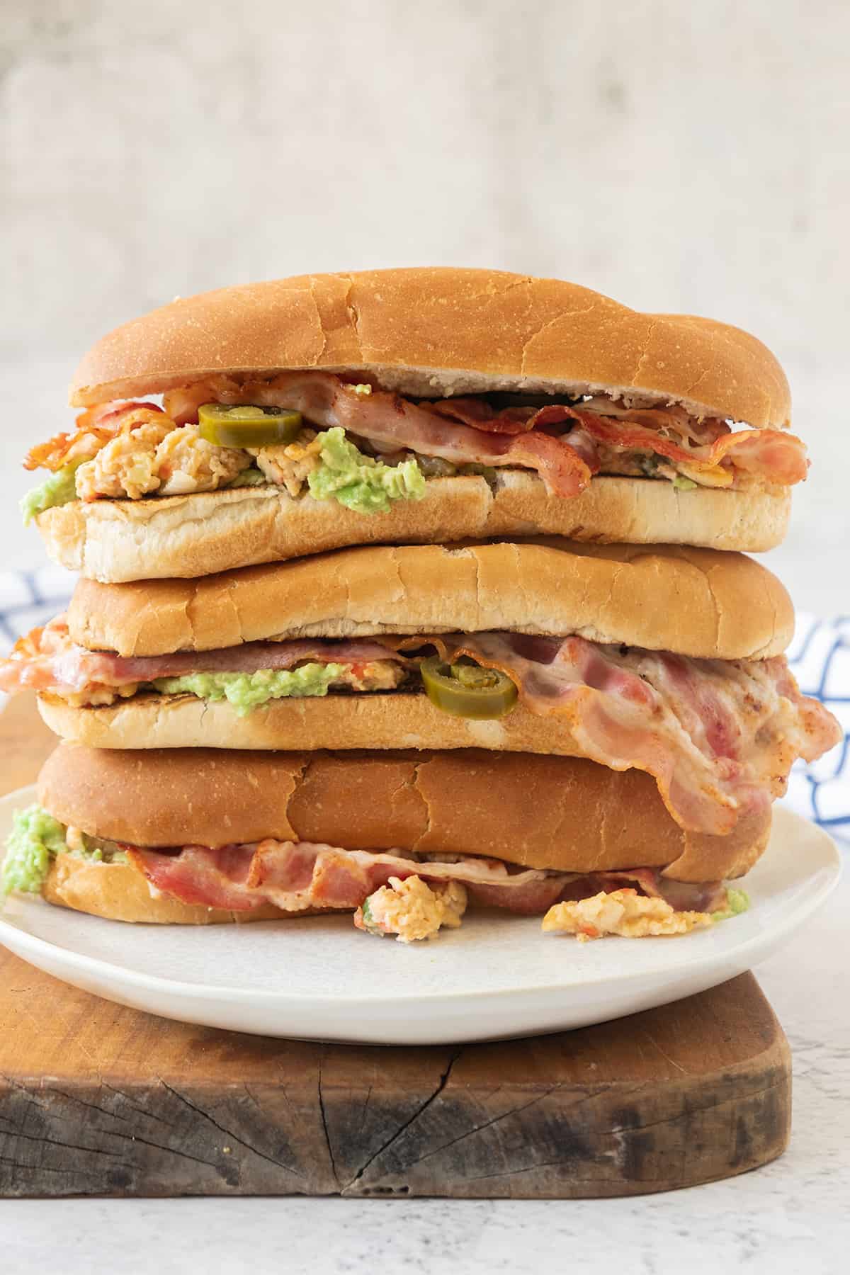 Three stacked Mexican Breakfast Tortas sitting on a white plate.