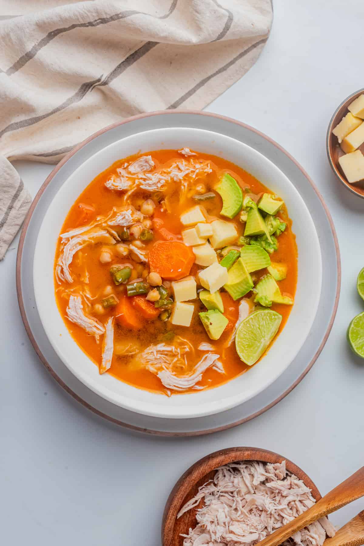 Caldo Tlalpeño served in a white bowl and topped with avocado and cheese cubes.