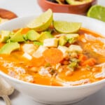 Caldo Tlalpeño served in a white bowl and topped with avocado and cubed cheese.