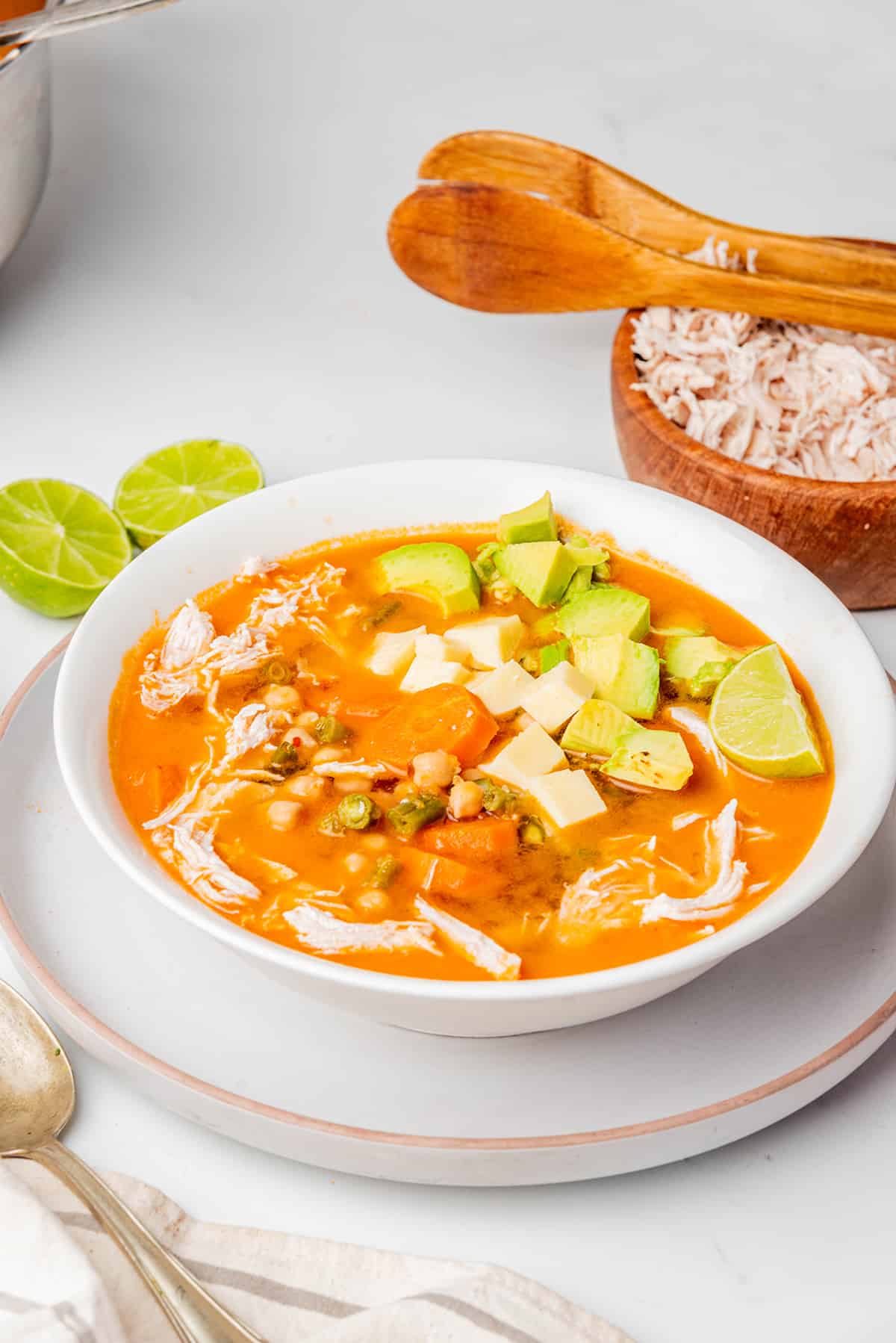 Caldo Tlalpeño served in a white bowl and topped with avocado and cheese.