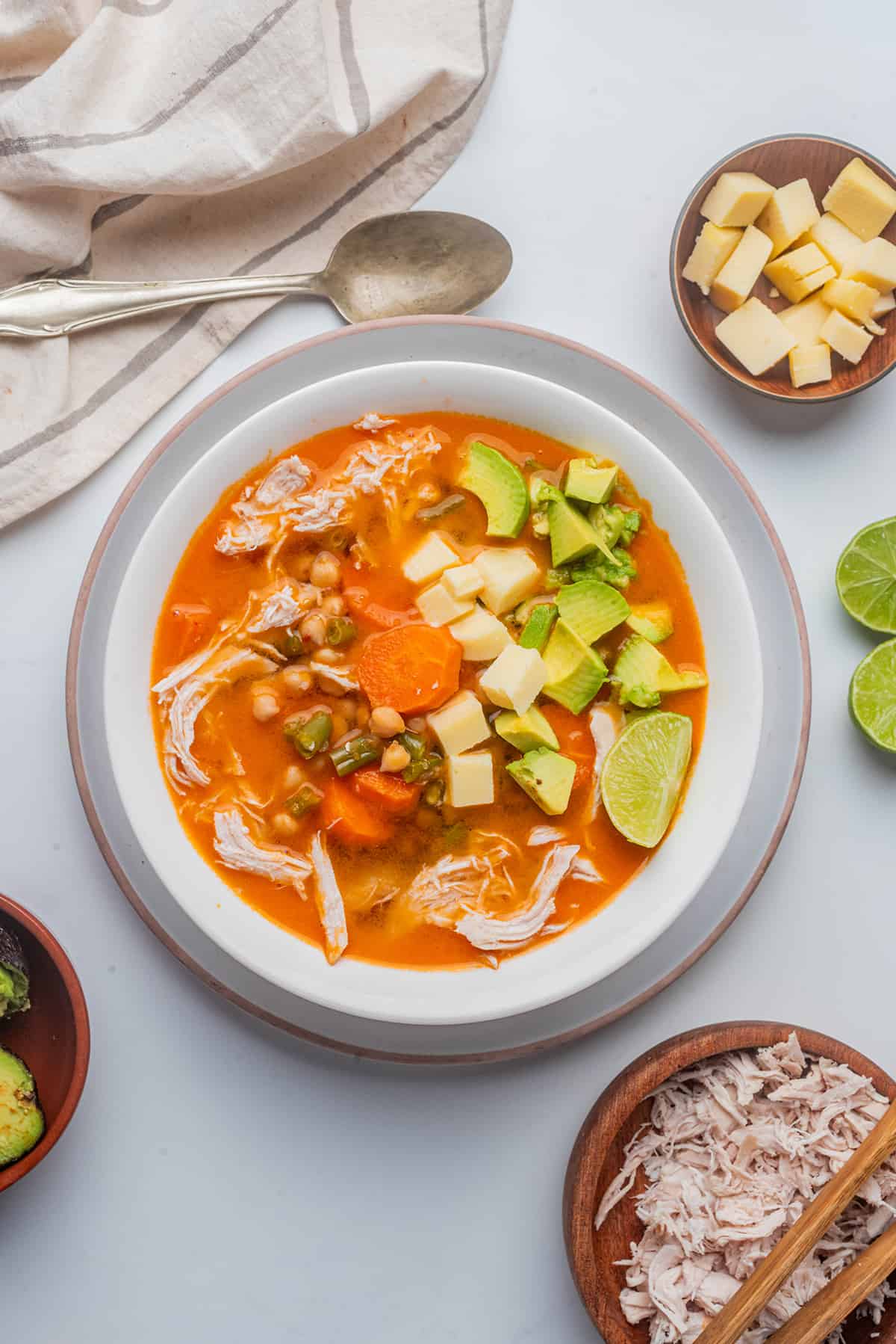 Caldo Tlalpeño served in a white bowl and topped with avocado and cheese.