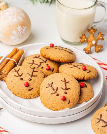 Gingerbread Reindeer Cookies in a white plate next to Christmas decorations.