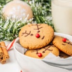 Gingerbread Reindeer Cookies in a white bowl next to Christmas decorations.