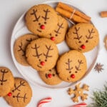 A plate of Gingerbread Reindeer Cookies next to candy canes and holiday decorations.