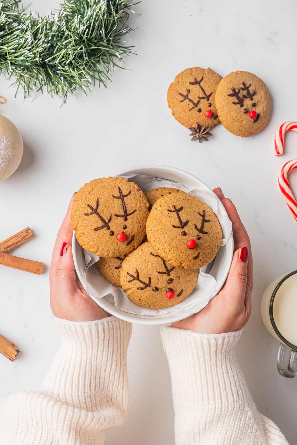 Hands holding a bowl of Gingerbread Reindeer cookies.