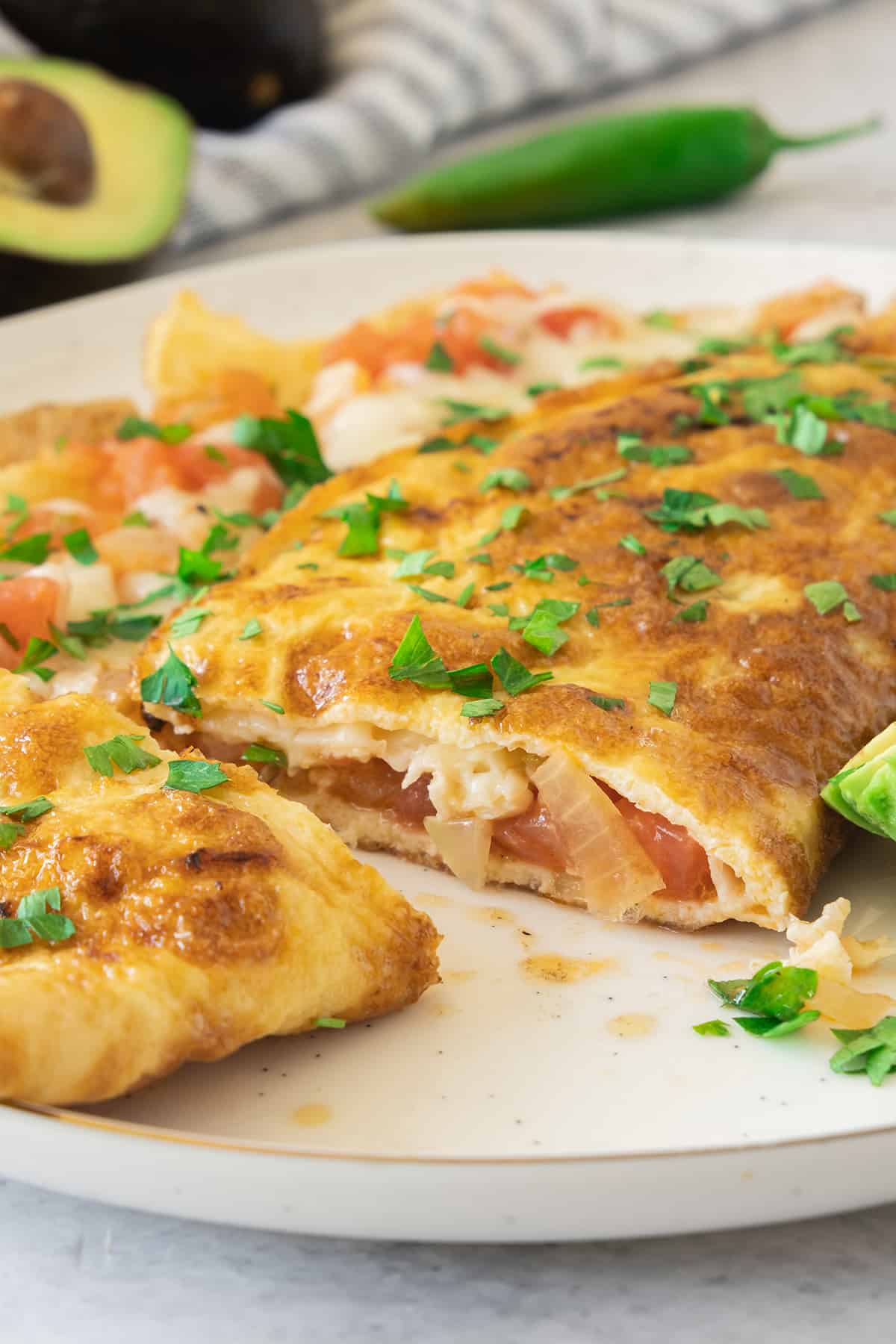 A Mexican omelet cut in half and topped with chopped cilantro.