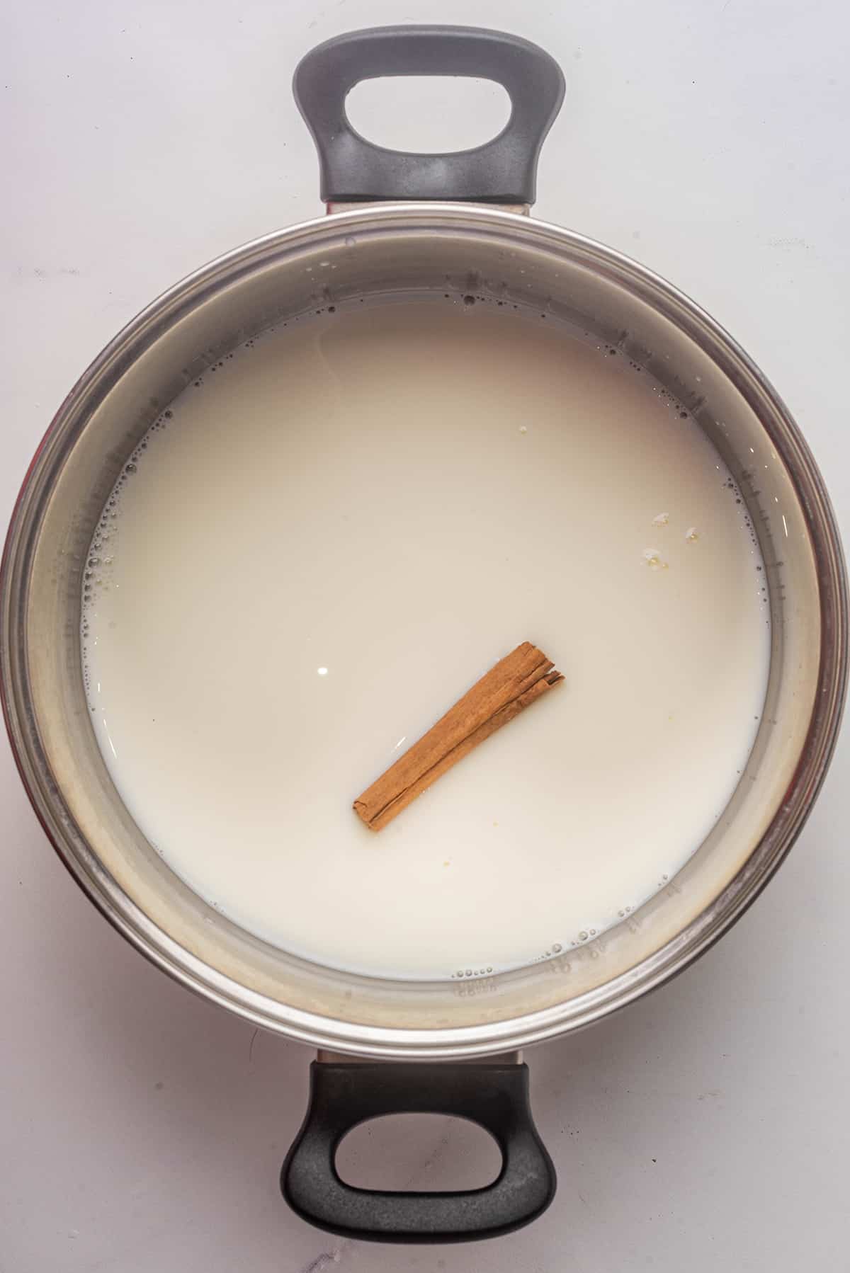 Milk and cinnamon simmering in a metal stock pot.
