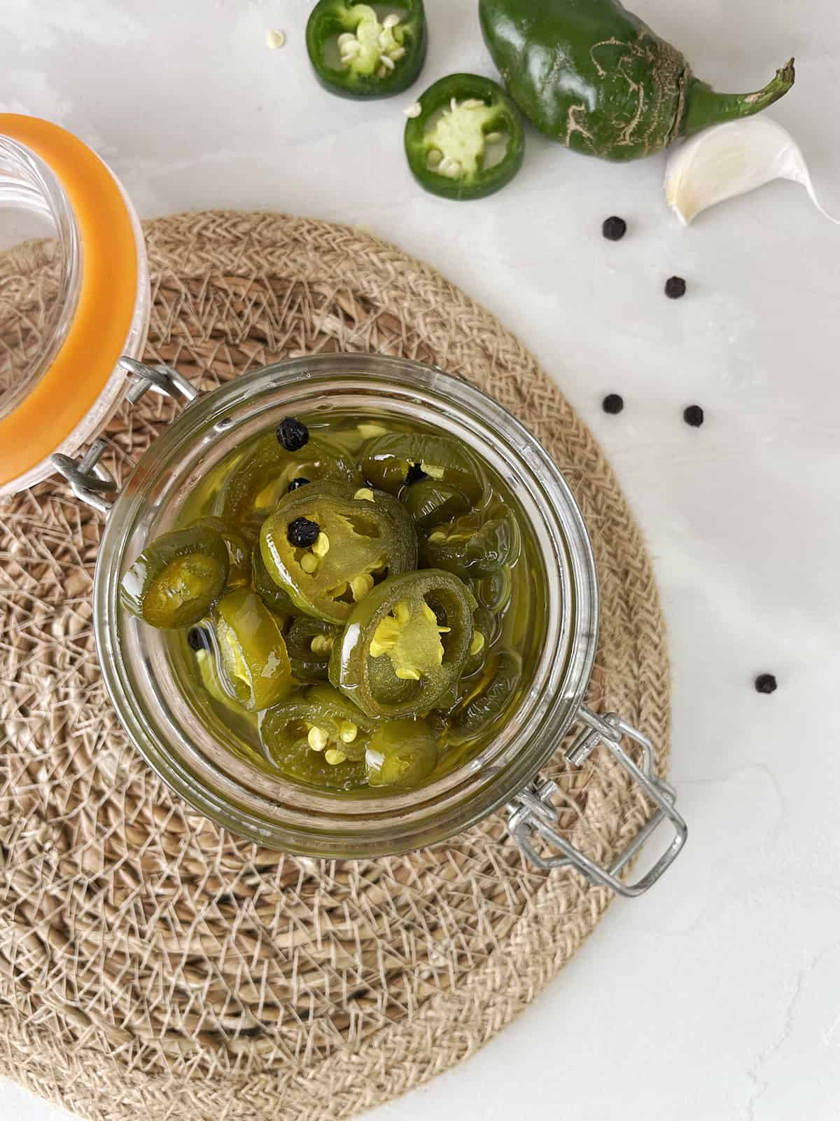 Sweet pickled jalapenos in a glass jar.