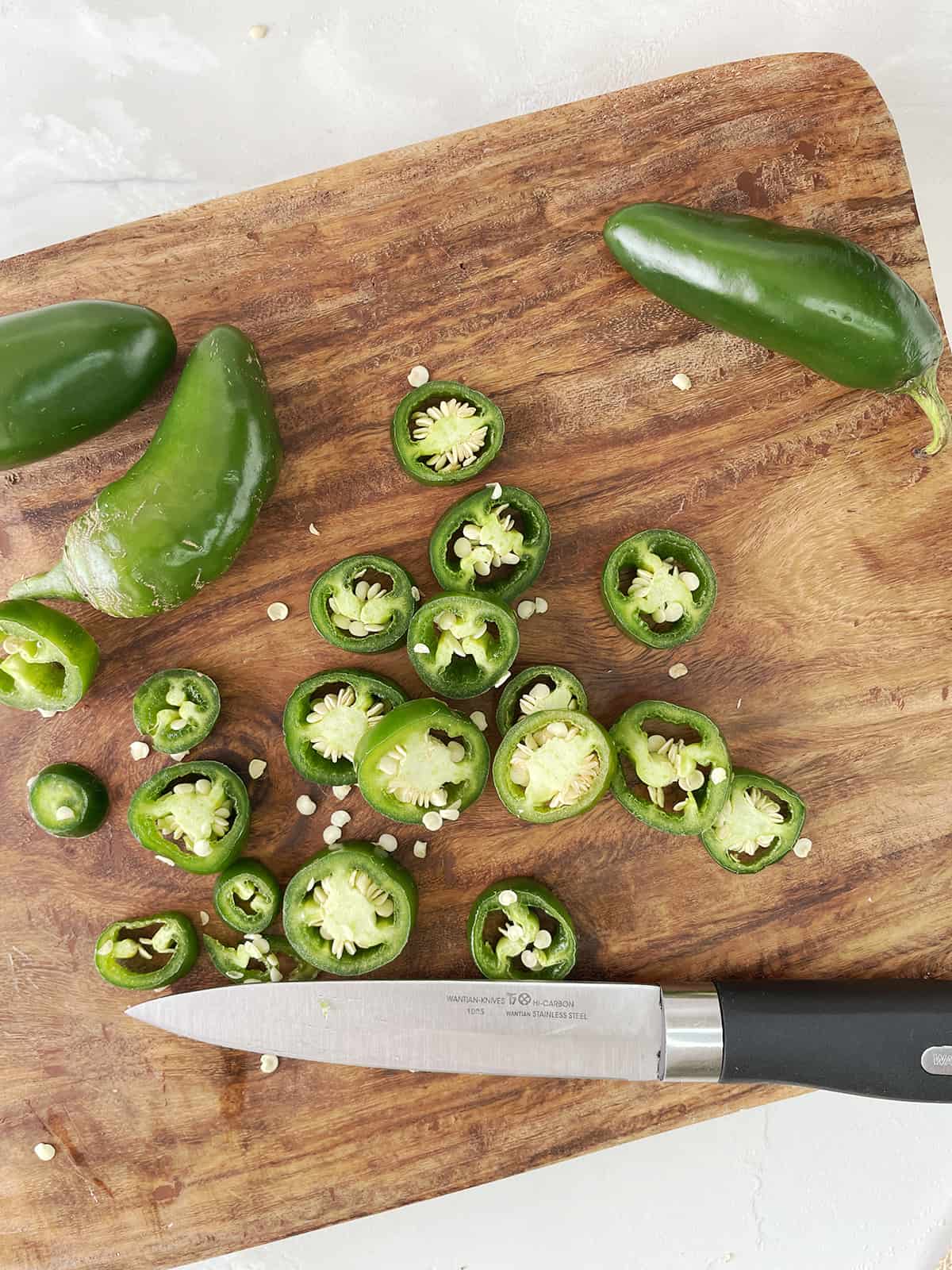 Sliced jalapenos on a cutting board.