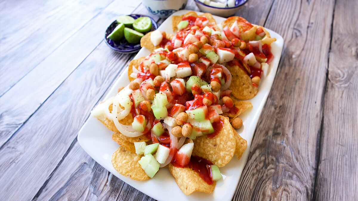 A plate of Tostilocos next to bowls with the ingredients needed to make the recipe.