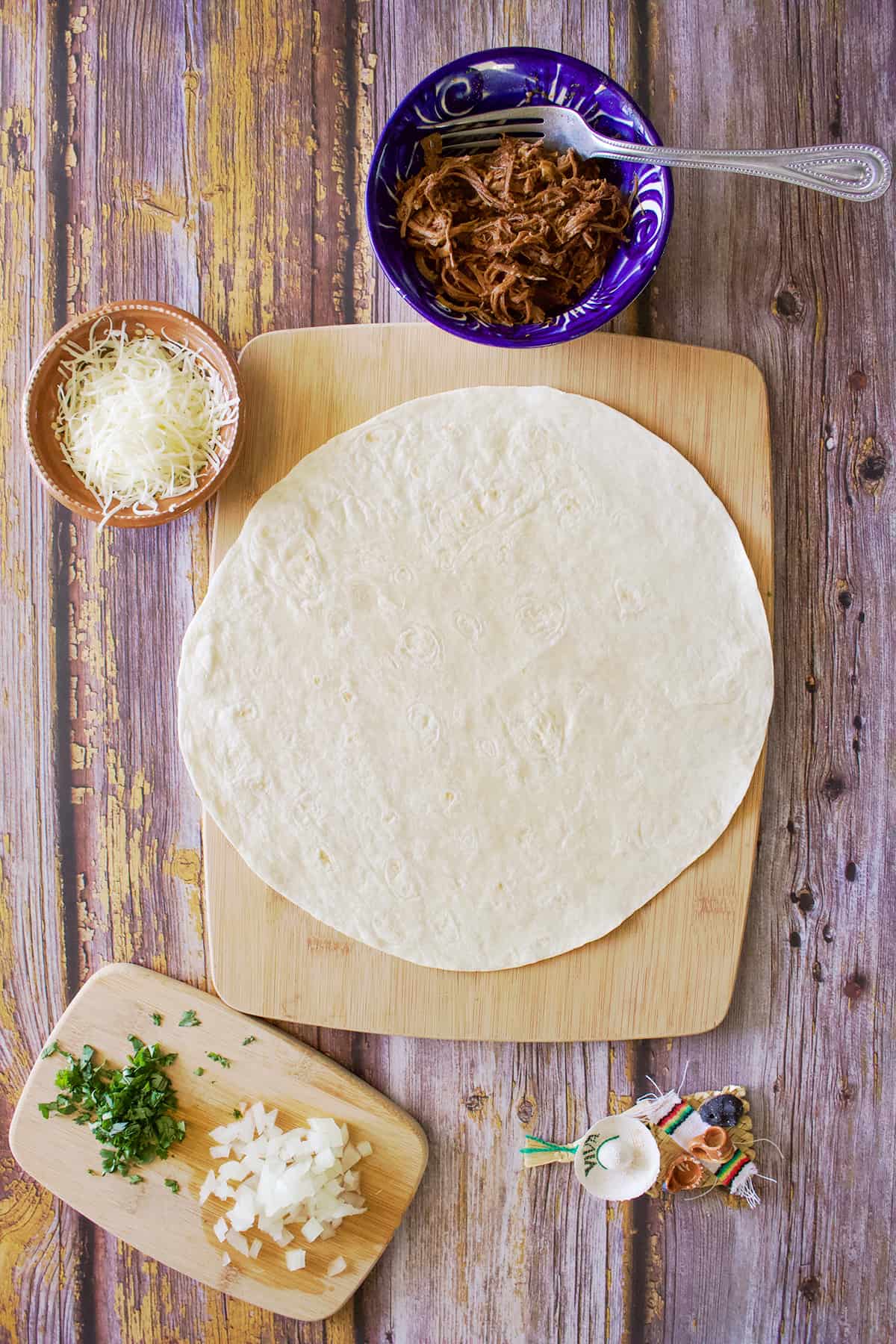 A burrito-sized flour tortilla next to the filling ingredients.