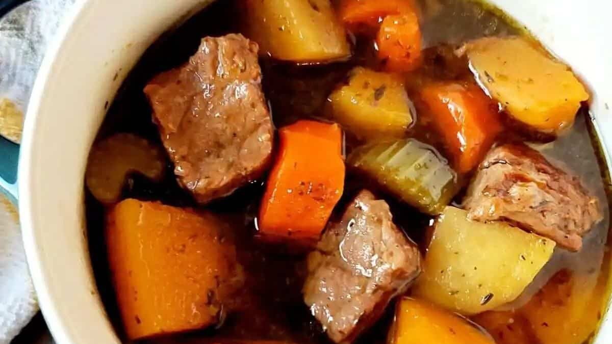 A bowl of hearty beef stew with chunks of tender beef, carrots, potatoes, and celery in a rich, savory broth.
