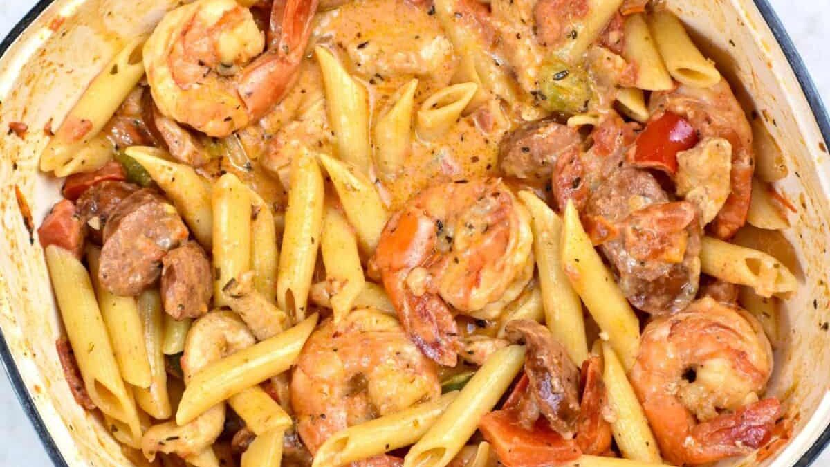 A close-up of a creamy pasta dish with shrimp, sliced sausage, and bell peppers. Penne pasta is mixed with a rich, seasoned sauce, creating a colorful and hearty meal.