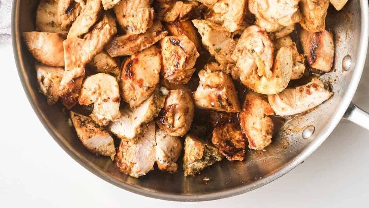 A pan filled with cooked, cubed chicken pieces, lightly browned and seasoned, is shown. The chicken is juicy and evenly distributed across the pan, creating a hearty and appetizing appearance.