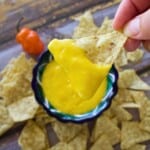 A hand holding a chip with mango habanero salsa.