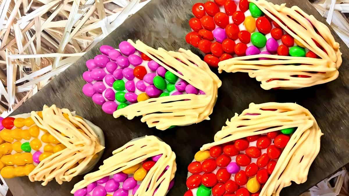 Colorful candy baskets made of twisted white icing and filled with vibrant round candies in red, purple, orange, green, and pink, arranged on a wooden surface.