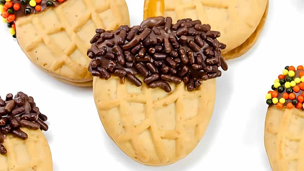 Acorn-shaped cookies decorated with chocolate sprinkles and colorful candy beads on a white background.