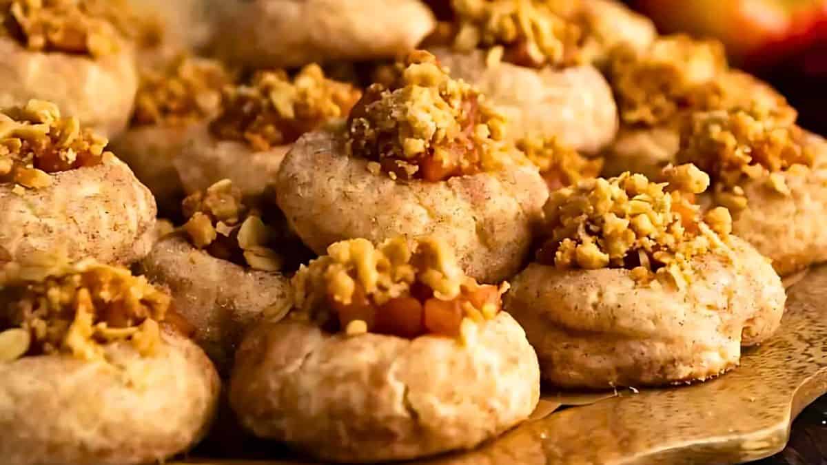 A plate of cinnamon sugar cookies topped with chopped walnuts and small apple pieces. The cookies are arranged closely together, showcasing a textured surface and a warm, inviting color.