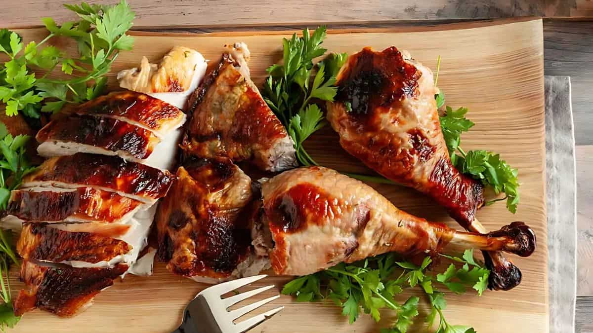 Grilled turkey pieces arranged on a wooden board, garnished with fresh parsley. A fork is placed nearby.