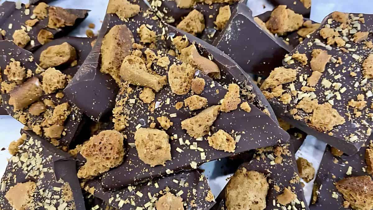 Close-up of dark chocolate bark topped with crumbled cookies. The rich chocolate pieces are generously sprinkled with cookie bits, creating a textured and appetizing appearance.