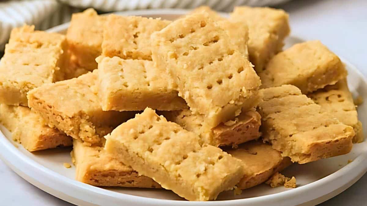 A plate of rectangular shortbread cookies stacked on top of each other. The cookies have a golden-brown color and feature fork-pricked patterns on their tops.