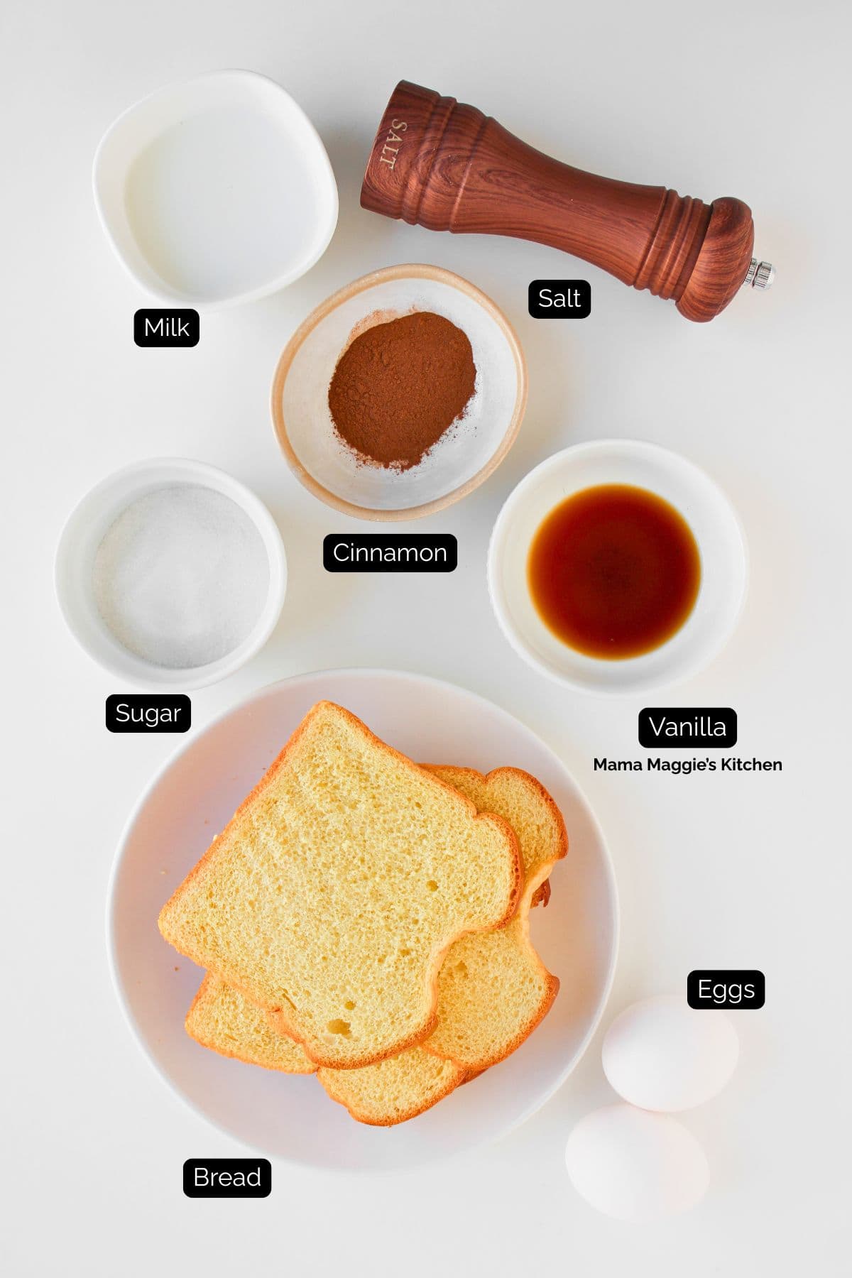 Top-down view of French toast ingredients: three slices of bread on a plate, two eggs, a bowl of sugar, a bowl of milk, a bowl of cinnamon, a bowl of vanilla, a salt shaker, all labeled with black text.