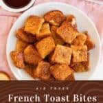 A white plate with golden brown Air Fryer French Toast Bites sits on a pink cloth, next to a bowl of syrup and a plate of fresh strawberries. Text below reads: "Air Fryer French Toast Bites - Mama Maggie's Kitchen.