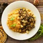 A plate of Mexican Picadillo with potatoes and a side of Mexican rice topped with cilantro.